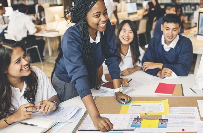 Group of young students at large table discussing a project