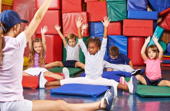 Children in PE class stretching their arms into the air