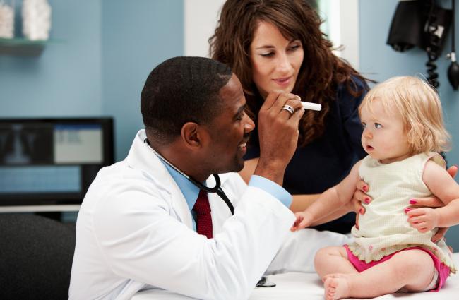 Doctor examining a baby with mom watching