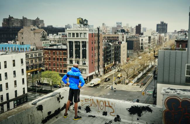 Man standing on roof of building looking out over a town center