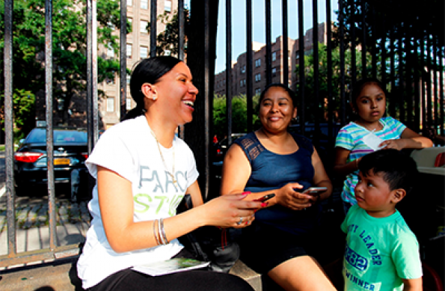 Group of women sitting on park bench with young child