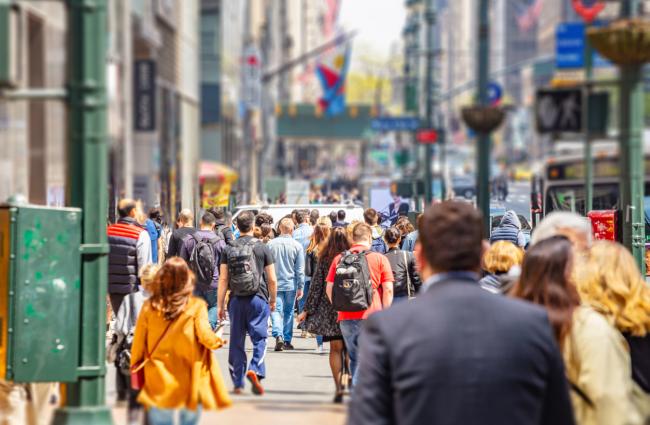 Image of a lot of people walking down a city sidewalk.