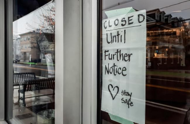 Storefront window with "Closed until further notice" sign in window due to COVID
