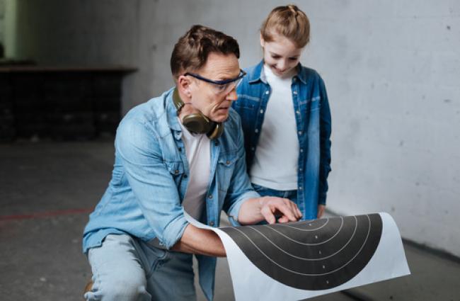 Man holding practice target talking with child