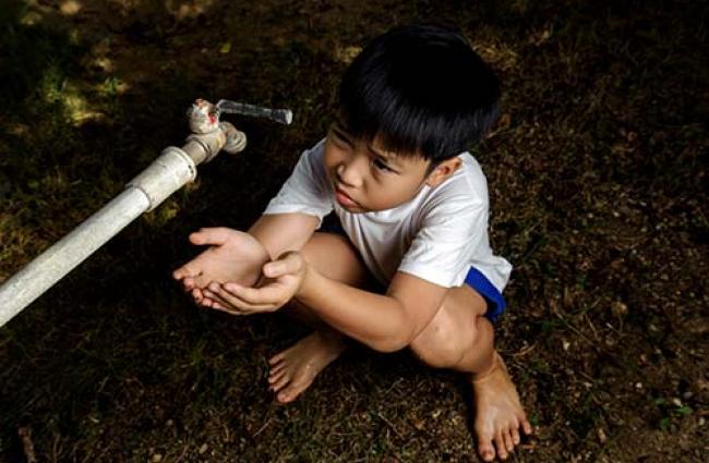 child drinking water with hands