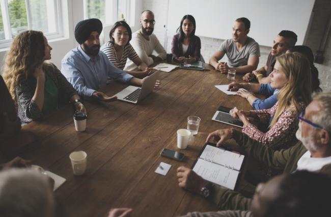 Group of individuals sitting around a table having a meeting