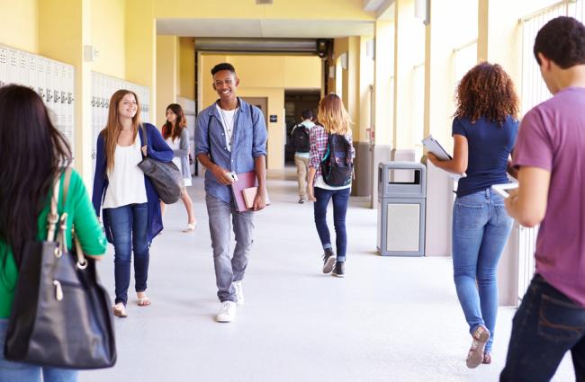 Adolescents walking down a bright school hallway