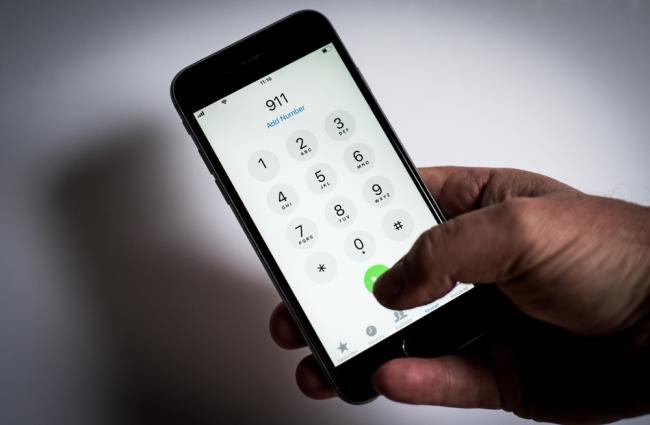 Black hand holding a phone dialing 911