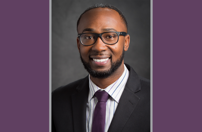 Dr. Charles Lea, a smiling Black man with short cropped hair, a beard, and a mustache. Dr. Lea is wearing glasses, a dark blazer, a striped shirt, and a dark plum tie