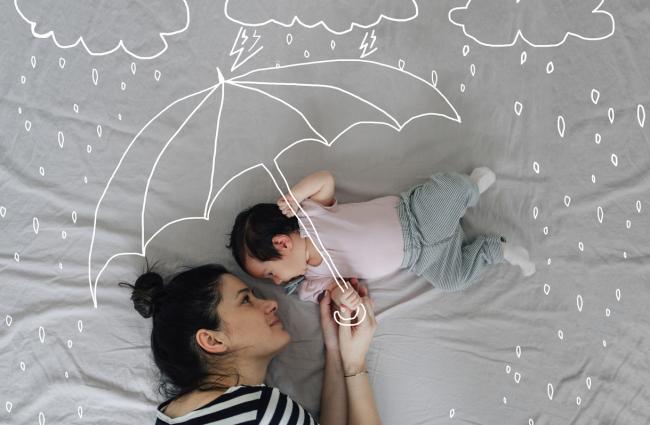 Woman and baby lying on a bed with an illustration of an umbrella over them shielding them from rain
