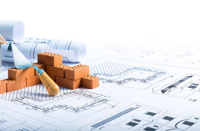 Model house being constructed on top of a set of blue prints