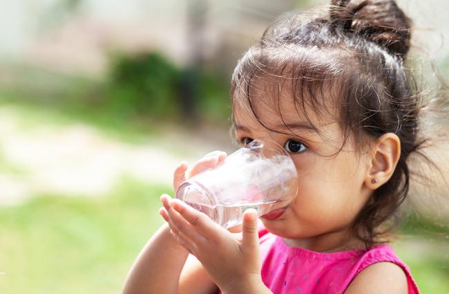 Little girl wearing a pink shirt drinking water