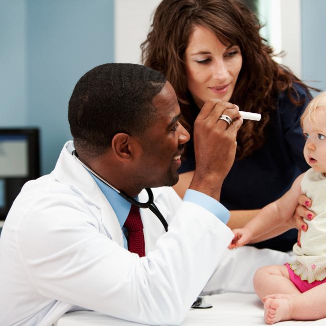 Doctor examining a baby with mom watching