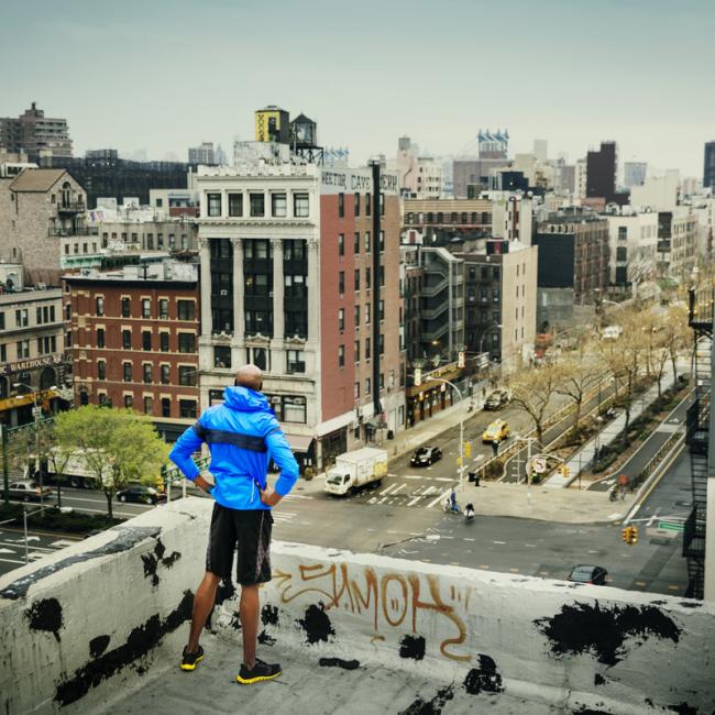 Man standing on roof of building looking out over a town center