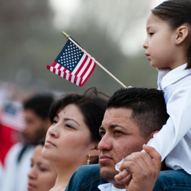 Father with child on his shoulders waving an American flag