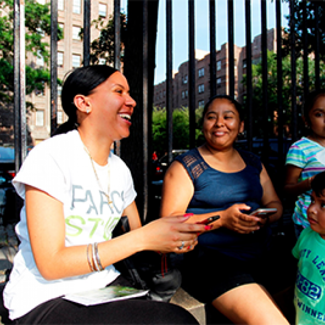 Group of women sitting on park bench with young child