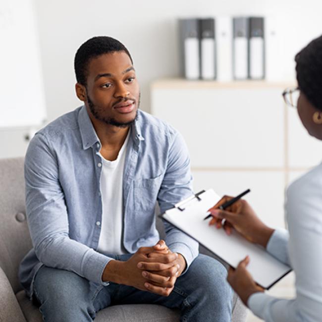 Serious looking young Black man being interviewed by a young Black woman in an office setting