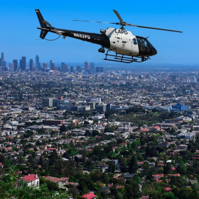 LAPD helicopter flying over residential area with LA skyline in the background