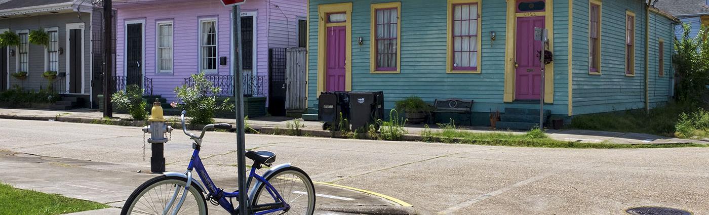 Bicycle against pole at street corner with houses in background