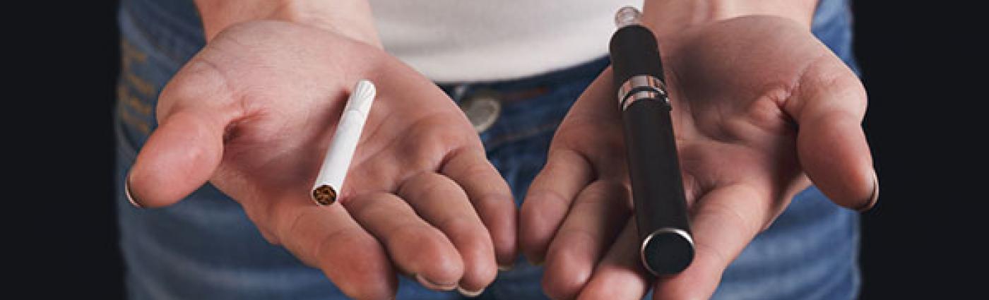 Image of a woman with a regular cigarette in one hand and an e-cigarette in the other.