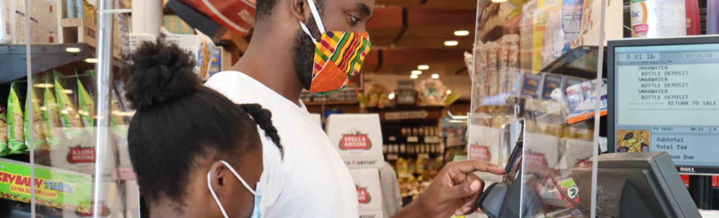 Black man and girl wearing face masks purchasing items at store during coronavirus pandemic