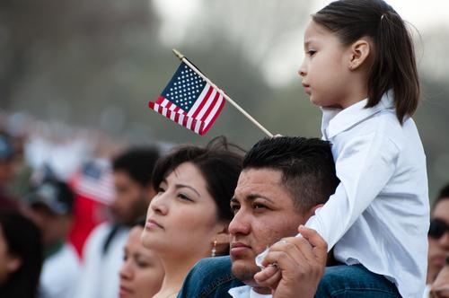 Father with child on his shoulders waving an American flag