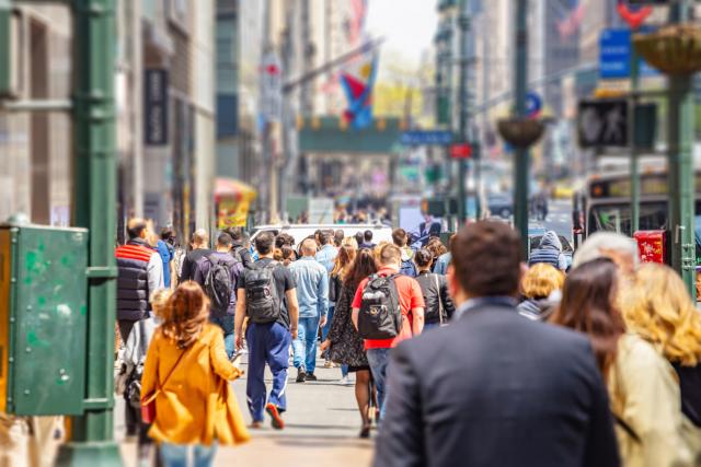 Image of a lot of people walking down a city sidewalk.