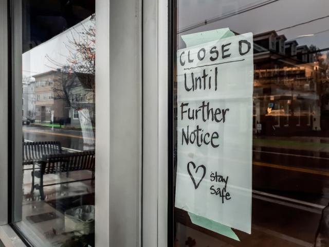 Storefront window with "Closed until further notice" sign in window due to COVID