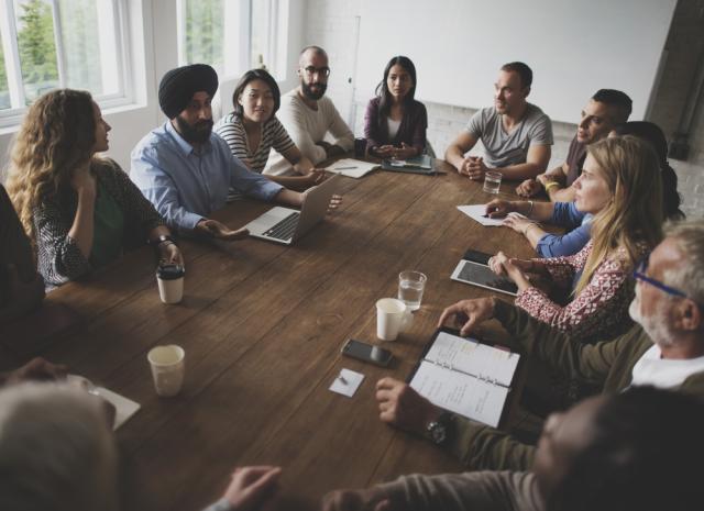 Group of individuals sitting around a table having a meeting