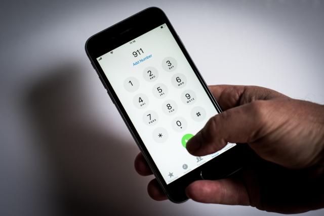Black hand holding a phone dialing 911