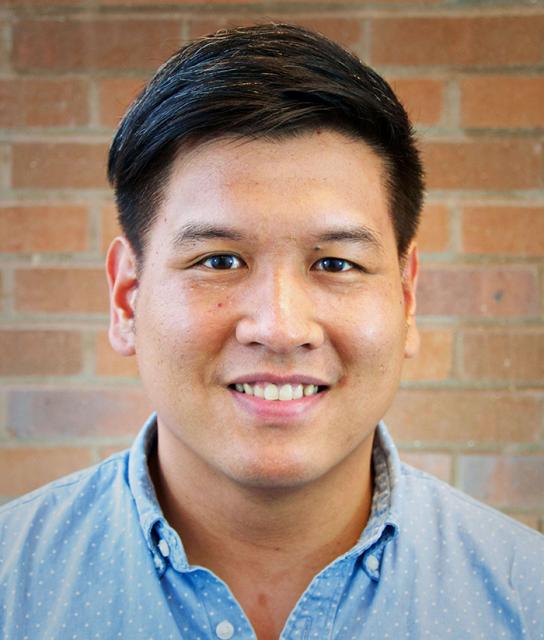 Dr. Bert Chantarat, a smiling man with short, dark hair, wearing a blue collared shirt in front of a brick wall